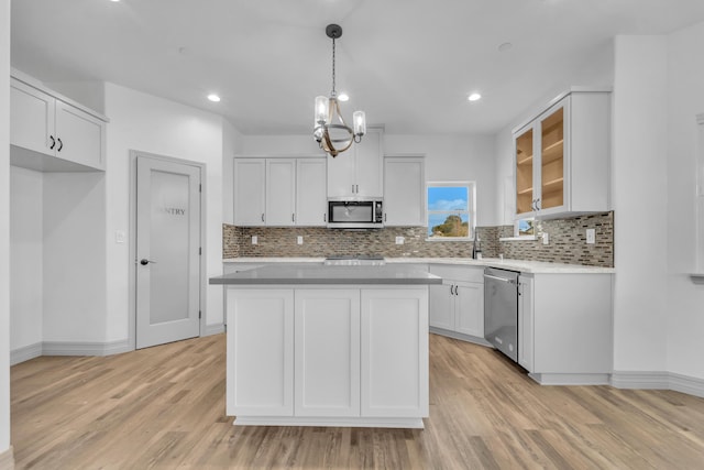 kitchen with hanging light fixtures, stainless steel appliances, a kitchen island, a chandelier, and white cabinets