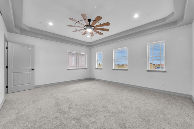 spare room with carpet, ceiling fan, and a tray ceiling