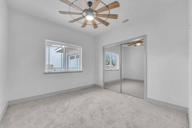 unfurnished bedroom featuring light colored carpet, a closet, and ceiling fan