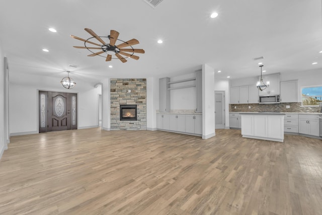 unfurnished living room featuring ceiling fan, a fireplace, and light wood-type flooring