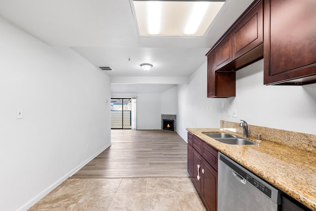 kitchen with dishwasher, light stone countertops, and sink