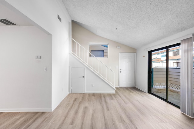 unfurnished living room with lofted ceiling, a textured ceiling, and light hardwood / wood-style flooring