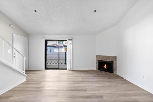 unfurnished living room with a tile fireplace, a textured ceiling, and light hardwood / wood-style floors