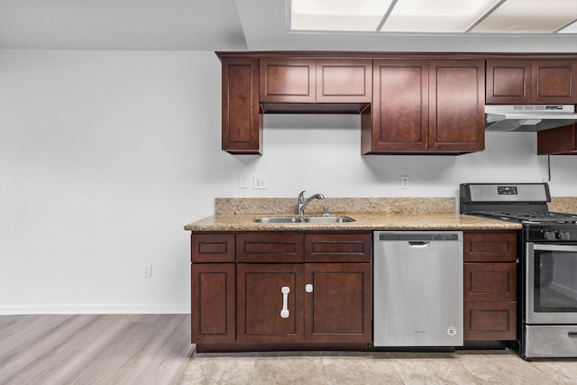 kitchen with light stone countertops, appliances with stainless steel finishes, light hardwood / wood-style flooring, and sink