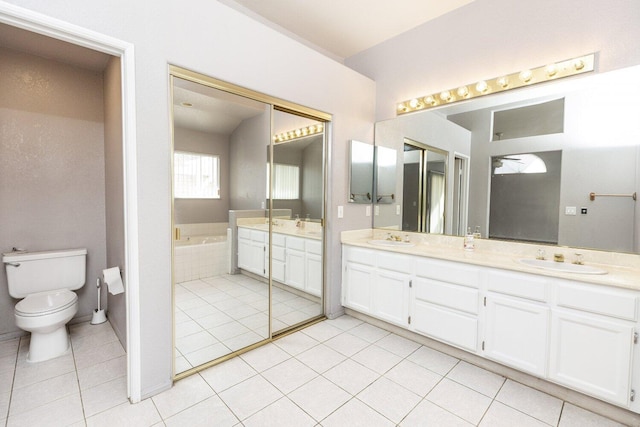 bathroom with tile patterned flooring, vanity, tiled bath, and toilet