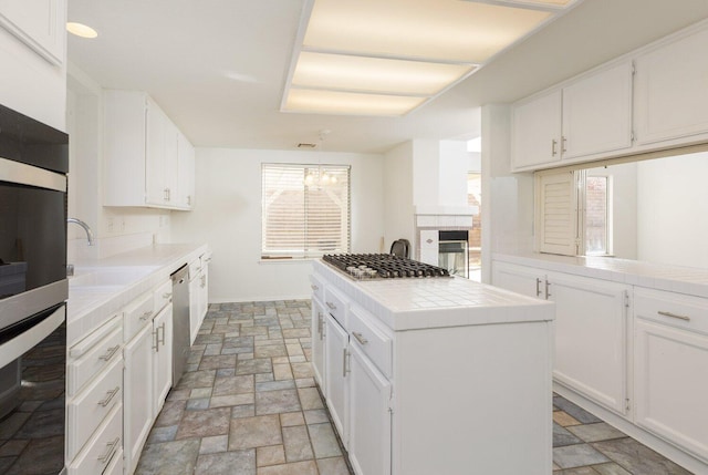 kitchen featuring sink, white cabinetry, appliances with stainless steel finishes, tile counters, and a kitchen island