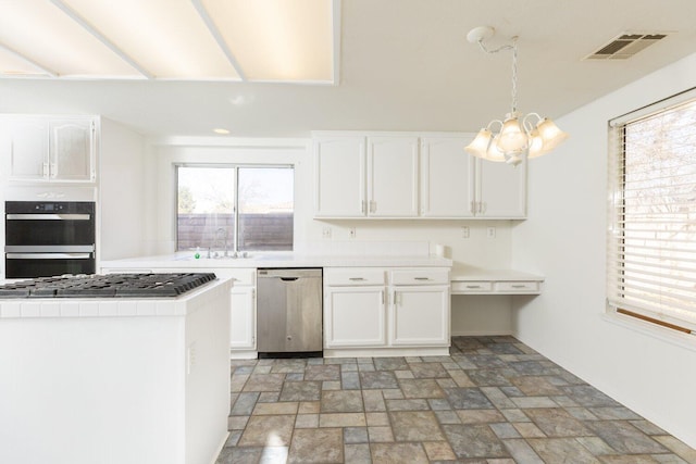 kitchen featuring appliances with stainless steel finishes, white cabinetry, hanging light fixtures, tile counters, and an inviting chandelier