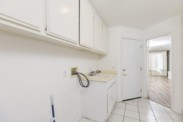 laundry area with sink, hookup for a washing machine, cabinets, and light tile patterned floors