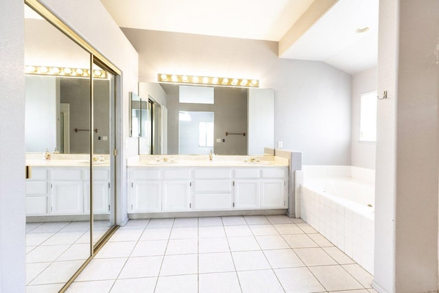 bathroom featuring lofted ceiling, tile patterned floors, tiled bath, and vanity