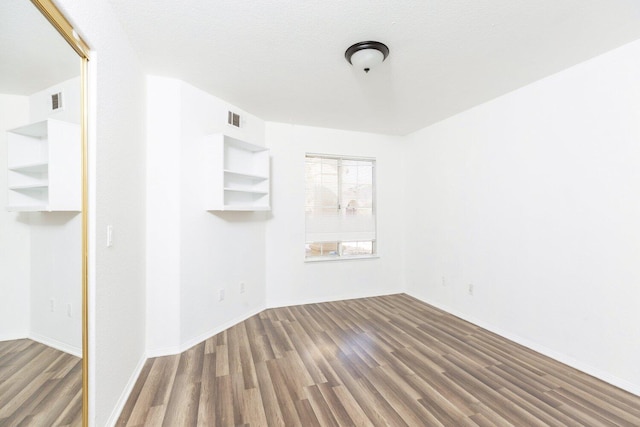 empty room with dark wood-type flooring and a textured ceiling