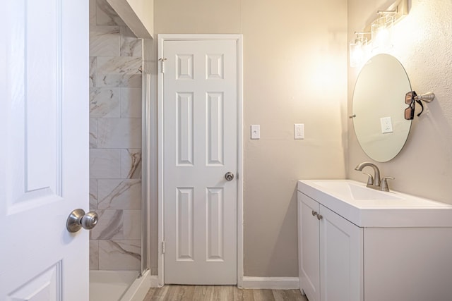 bathroom with tiled shower, wood-type flooring, and vanity