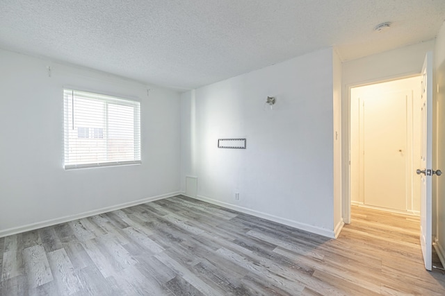 unfurnished room with a textured ceiling and light hardwood / wood-style flooring