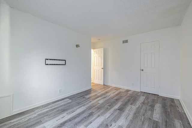 spare room featuring light hardwood / wood-style flooring and a textured ceiling