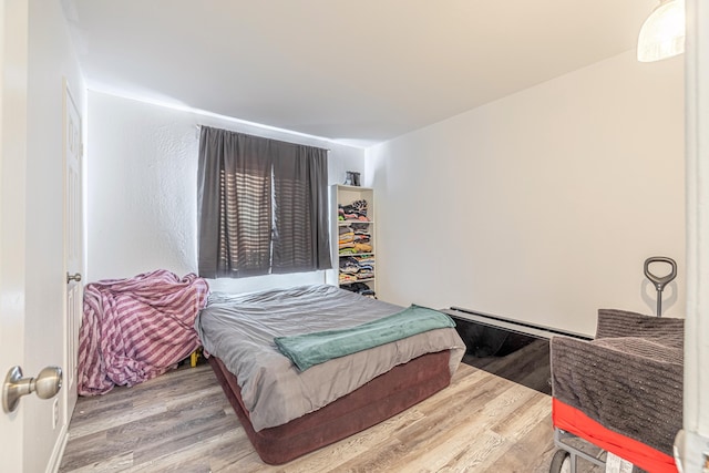 bedroom featuring wood-type flooring and a baseboard radiator