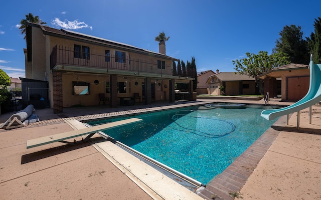 view of swimming pool featuring a diving board, a patio area, and a water slide