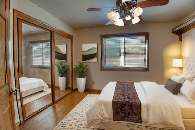 bedroom with multiple windows, light wood-type flooring, and ceiling fan