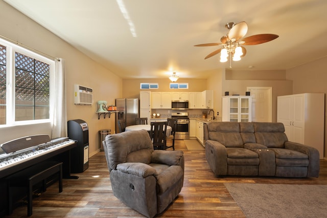 living room with dark hardwood / wood-style floors, ceiling fan, sink, and a wall unit AC