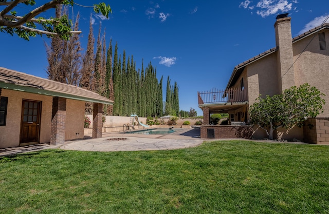 view of yard with a patio area, a balcony, and a fenced in pool