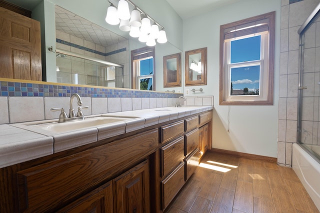 bathroom with decorative backsplash, vanity, hardwood / wood-style flooring, and enclosed tub / shower combo