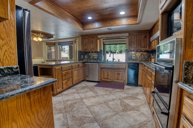 kitchen featuring tasteful backsplash, a tray ceiling, ceiling fan, and sink