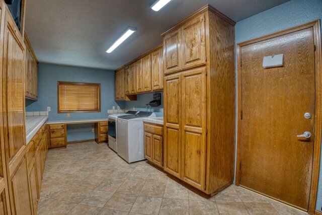 laundry room with washer and dryer, cabinets, and a textured ceiling