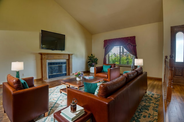 living room with hardwood / wood-style flooring, high vaulted ceiling, and a tiled fireplace