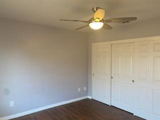 unfurnished bedroom with ceiling fan, a closet, and dark hardwood / wood-style floors