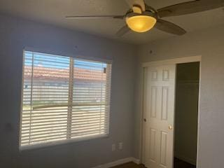 unfurnished bedroom featuring ceiling fan, multiple windows, and a closet