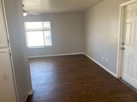 empty room with ceiling fan and dark hardwood / wood-style flooring