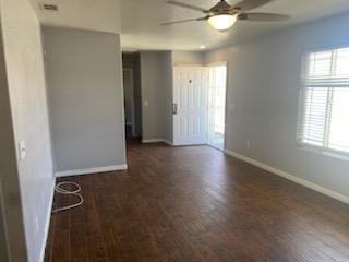 unfurnished room featuring ceiling fan, dark wood-type flooring, and a wealth of natural light