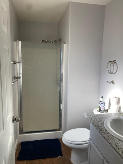 bathroom with wood-type flooring, vanity, toilet, and a shower with door