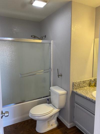 full bathroom with hardwood / wood-style floors, vanity, toilet, and enclosed tub / shower combo