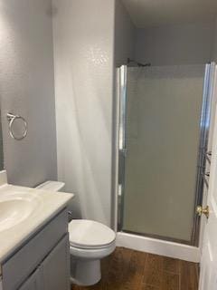 bathroom featuring vanity, toilet, a shower with door, and wood-type flooring