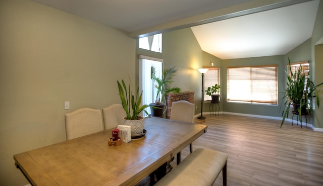 dining room featuring vaulted ceiling, plenty of natural light, wood finished floors, and baseboards