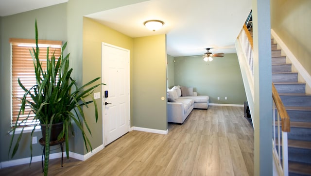 entrance foyer with light wood-type flooring, ceiling fan, stairs, and baseboards