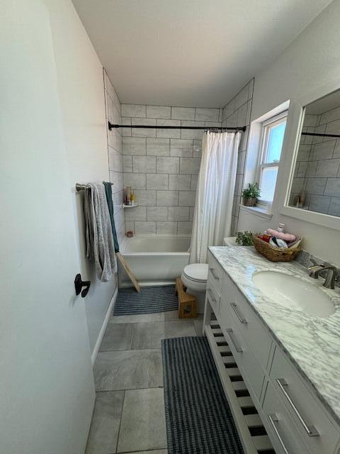 bathroom featuring shower / tub combo, tile patterned flooring, vanity, and toilet