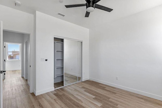 unfurnished bedroom featuring ceiling fan, light hardwood / wood-style floors, and a closet