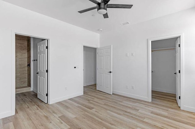 unfurnished bedroom with a closet, a spacious closet, light hardwood / wood-style flooring, and ceiling fan