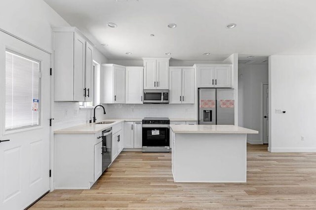 kitchen featuring white cabinets, a center island, sink, and appliances with stainless steel finishes