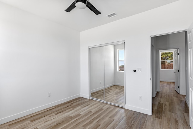 unfurnished bedroom featuring ceiling fan, a closet, and light wood-type flooring