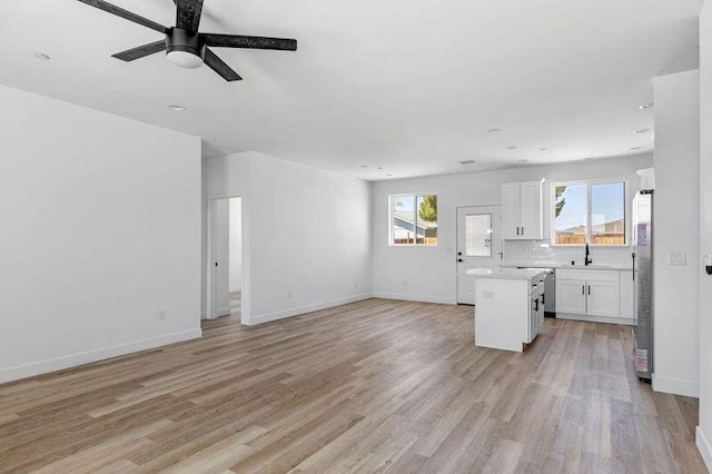 interior space with ceiling fan, sink, a kitchen island, light hardwood / wood-style floors, and white cabinets