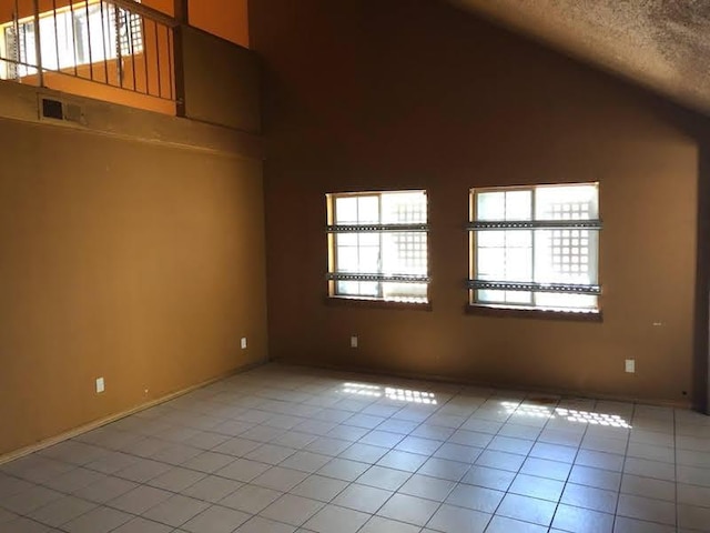 1132 Morven St, Lancaster, CA 93535 - empty room with vaulted ceiling, light tile patterned floors, a textured ceiling, and baseboards