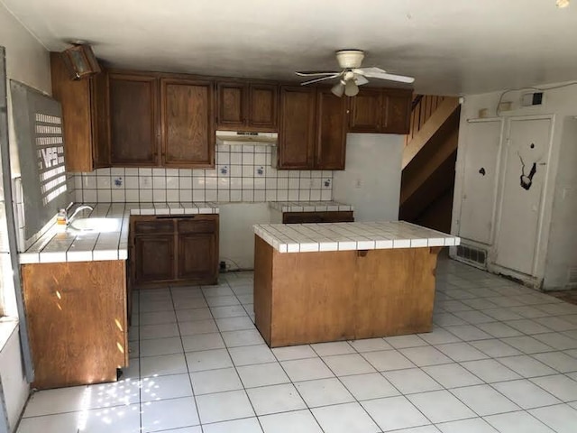 1132 Morven St, Lancaster, CA 93535 - kitchen featuring a ceiling fan, tile counters, tasteful backsplash, under cabinet range hood, and a sink