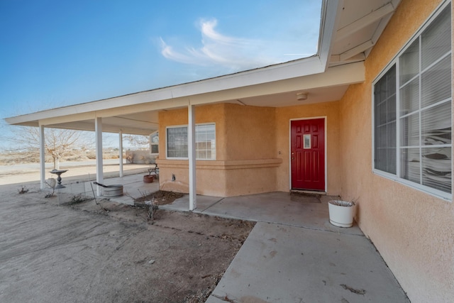 view of exterior entry featuring a patio area and stucco siding