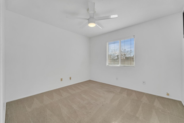 empty room featuring baseboards, a ceiling fan, and light colored carpet