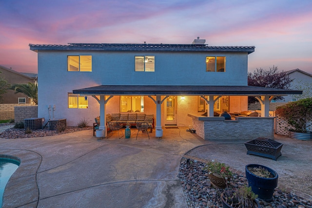 4104 Rainer Pl, Quartz Hill, CA 93536 - back of house at dusk featuring a patio, an outdoor living space with a fire pit, exterior kitchen, and stucco siding