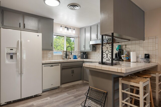 43818 Halcom Ave, Lancaster, CA 93536 - kitchen with white appliances, gray cabinetry, a sink, tile countertops, and light wood-style flooring
