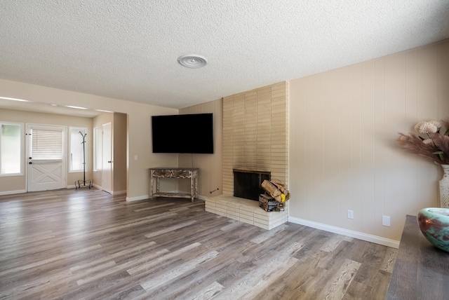 43818 Halcom Ave, Lancaster, CA 93536 - living room featuring wood finished floors, a textured ceiling, a brick fireplace, and baseboards
