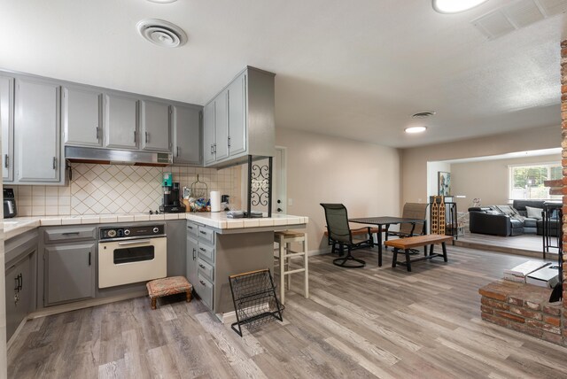 43818 Halcom Ave, Lancaster, CA 93536 - kitchen with oven, gray cabinets, tile countertops, and under cabinet range hood