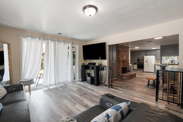 43818 Halcom Ave, Lancaster, CA 93536 - living room featuring light wood-type flooring and a brick fireplace